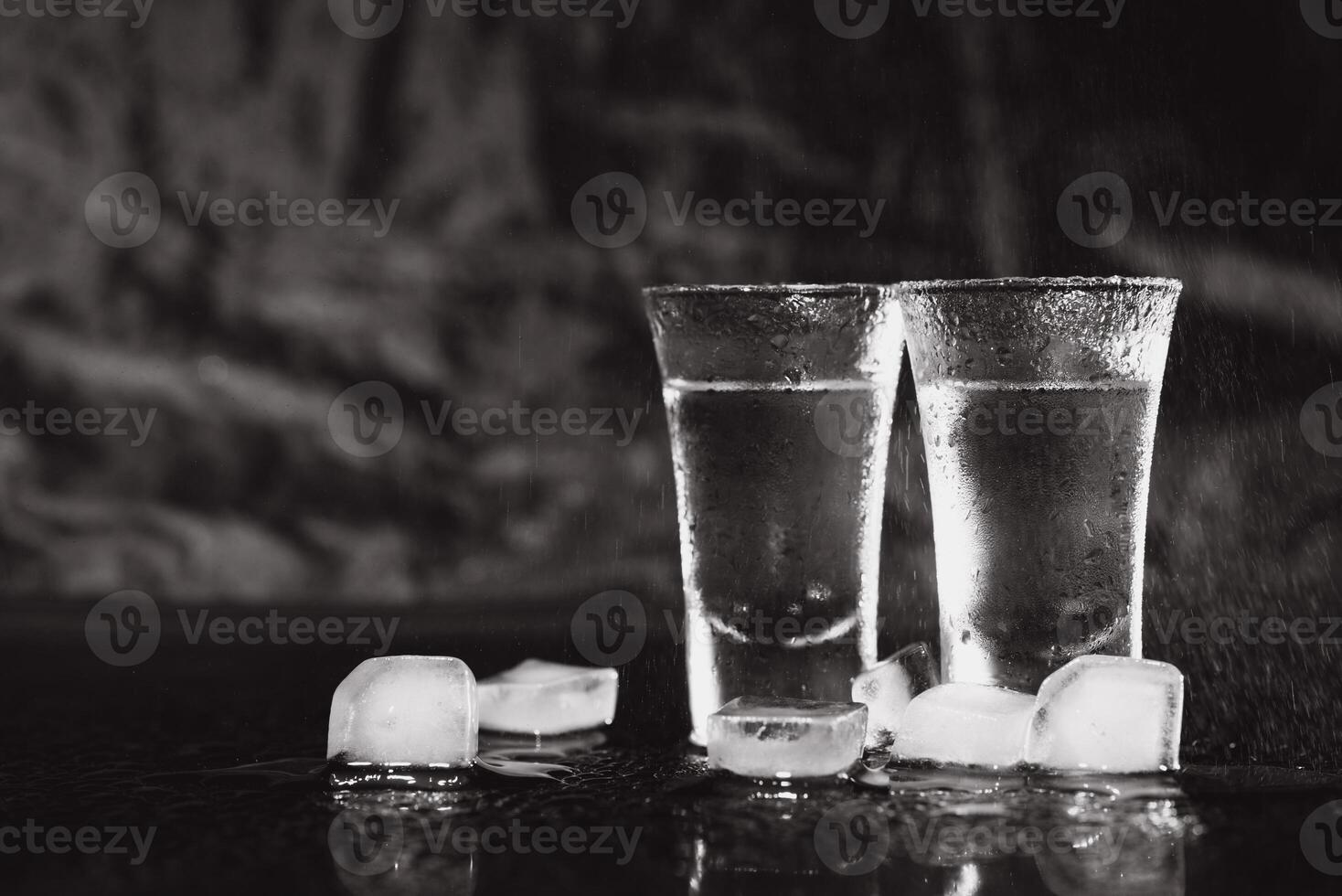 Vodka shots with ice on black table, copy space. photo