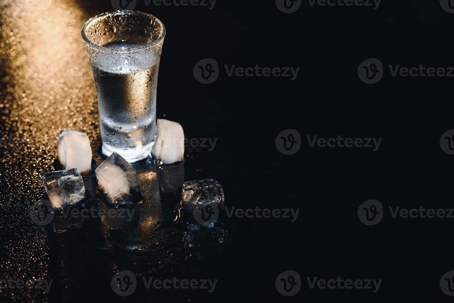 Vodka shots with ice on black table, copy space. photo