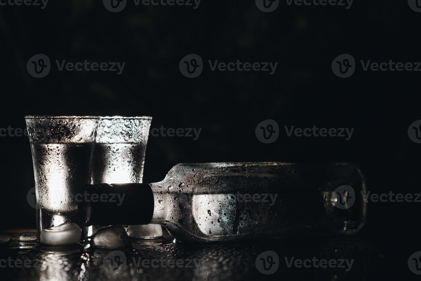 Vodka in shot glasses on dark background photo
