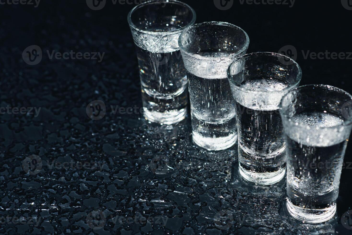 Vodka in shot glasses on dark background photo