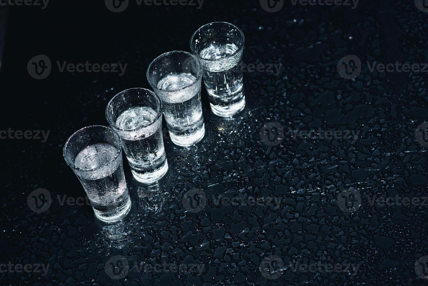 Vodka in shot glasses on dark background photo