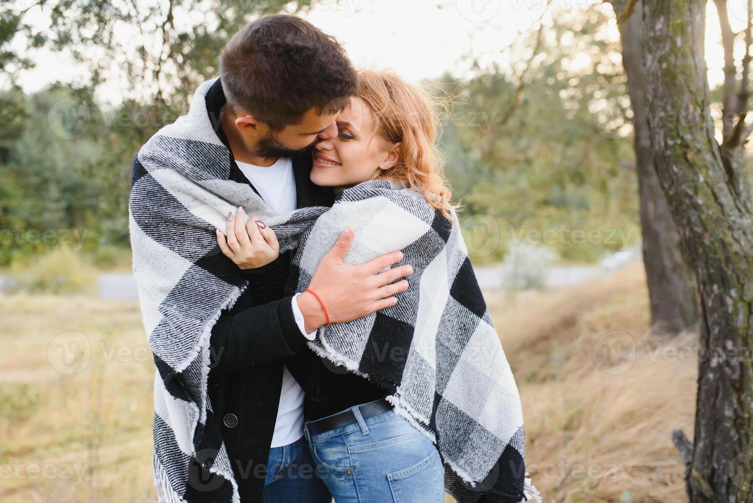 young romantic couple in love in a gentle hug and warm themselves with a plaid, the concept of romantic love relationships. photo