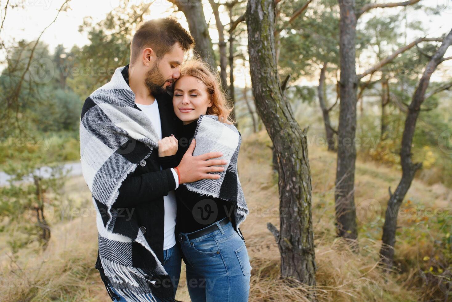 young romantic couple in love in a gentle hug and warm themselves with a plaid, the concept of romantic love relationships. photo