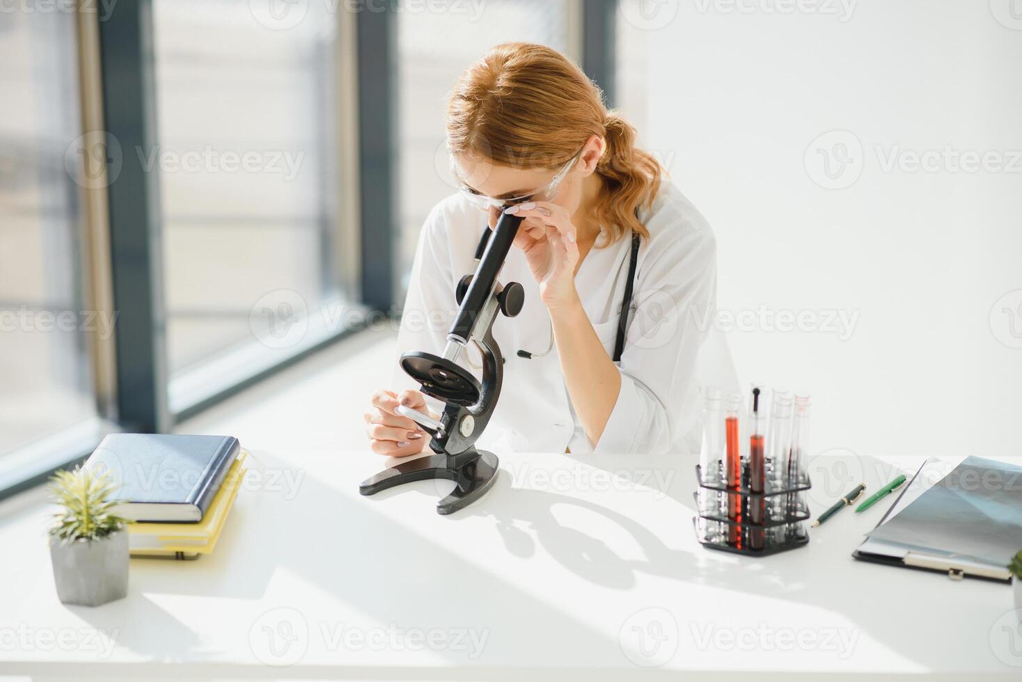 Doctor woman working a microscope. Female scientist looking through a microscope in lab. Student looking in a microscope, science laboratory concept. photo
