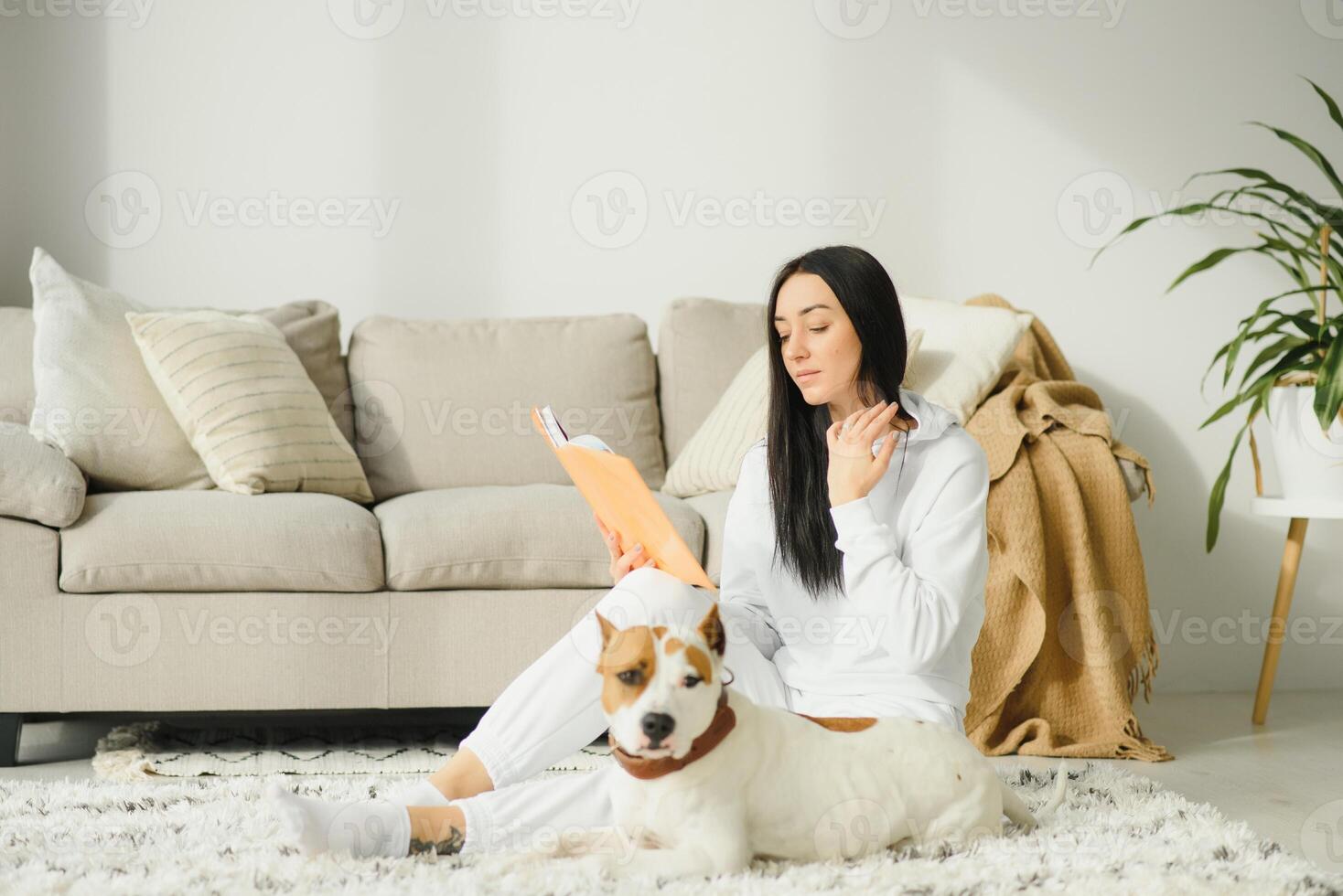A beautiful young woman reading her favorite book with her dog. photo