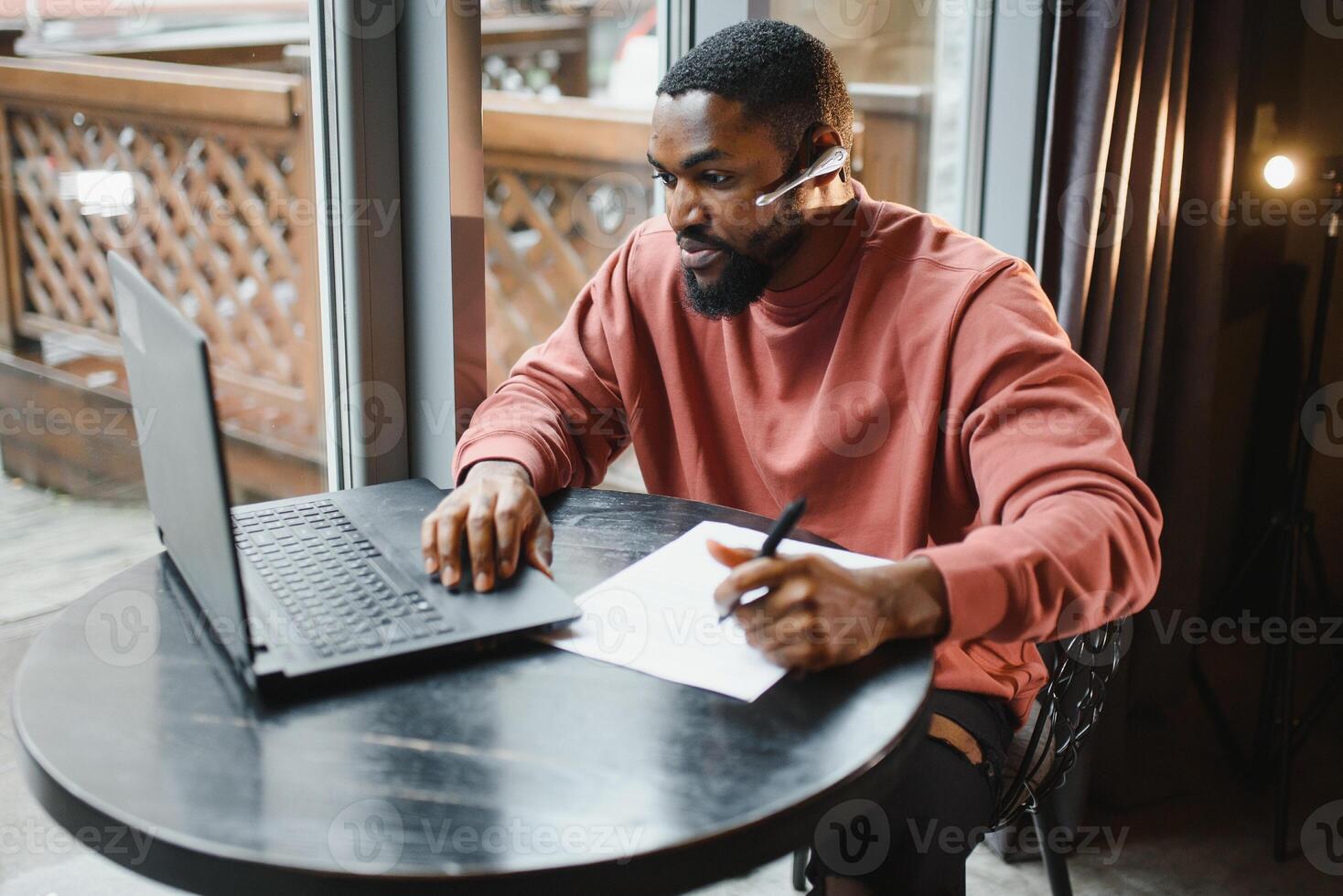 Afro american talks chat on computer sits in cafe with cup of coffee. Black man calls on laptop on link and speaks. He wears in shirt and suit jacket. link online connection photo