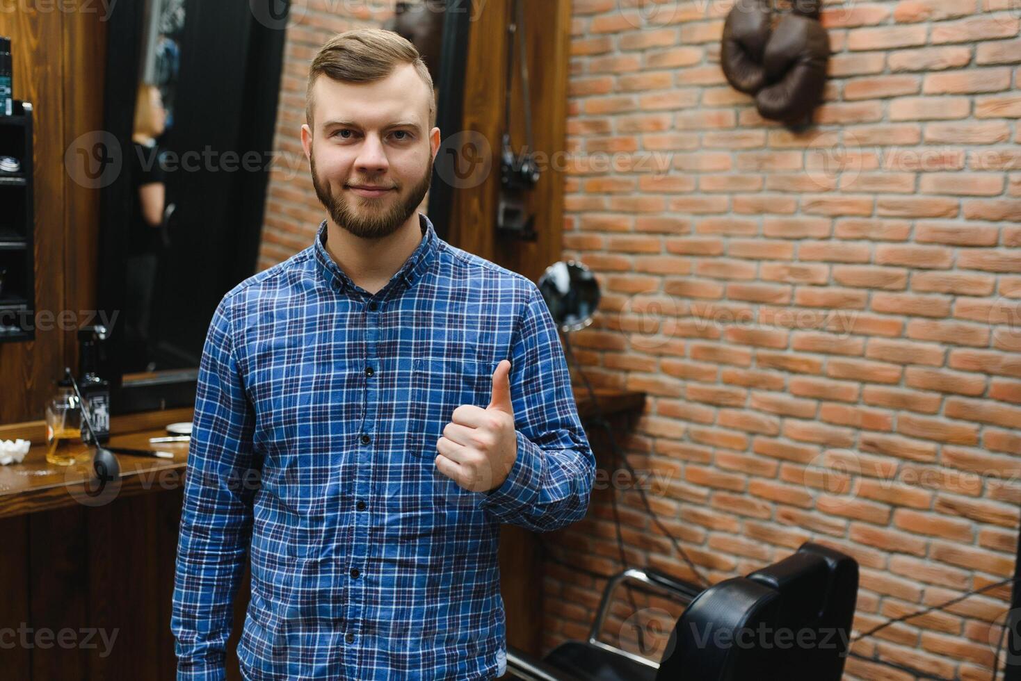 Perfection. Handsome bearded man at barbershop. Portrait of stylish young guy in jacket touching his hair while visiting barbershop or salon. Mens haircut. Barbershop concept photo