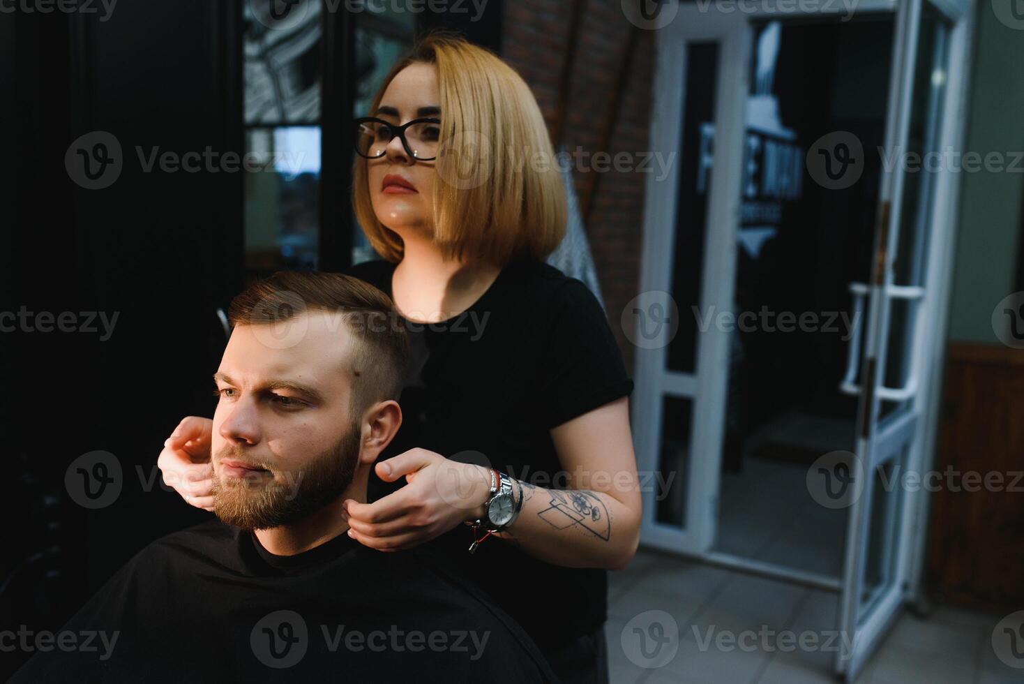Client during beard shaving in barber shop photo