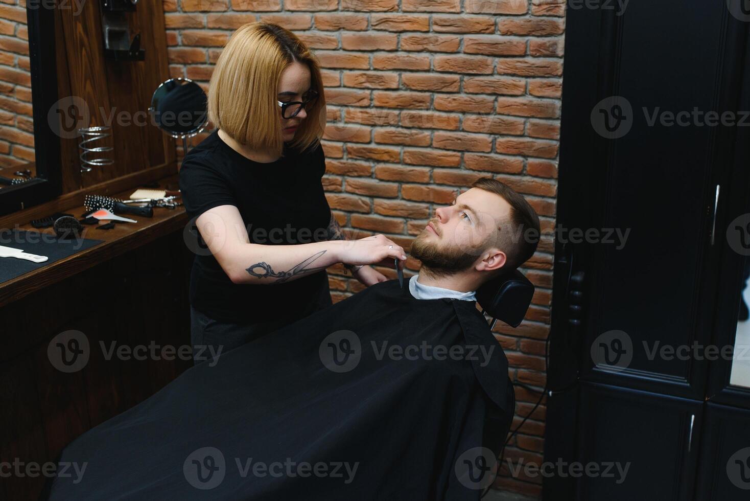 Client during beard shaving in barber shop photo