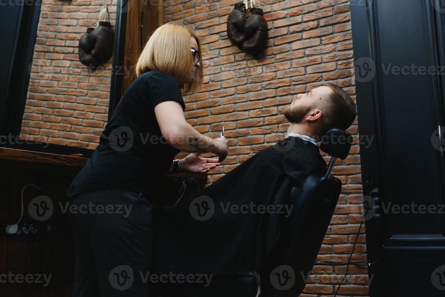 Barbershop or hairdresser concept. Woman hairdresser cuts beard with scissors. Man with long beard, mustache and stylish hair. Guy with modern hairstyle visiting hairdresser photo