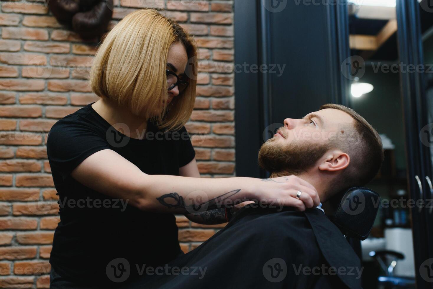Client during beard shaving in barber shop photo