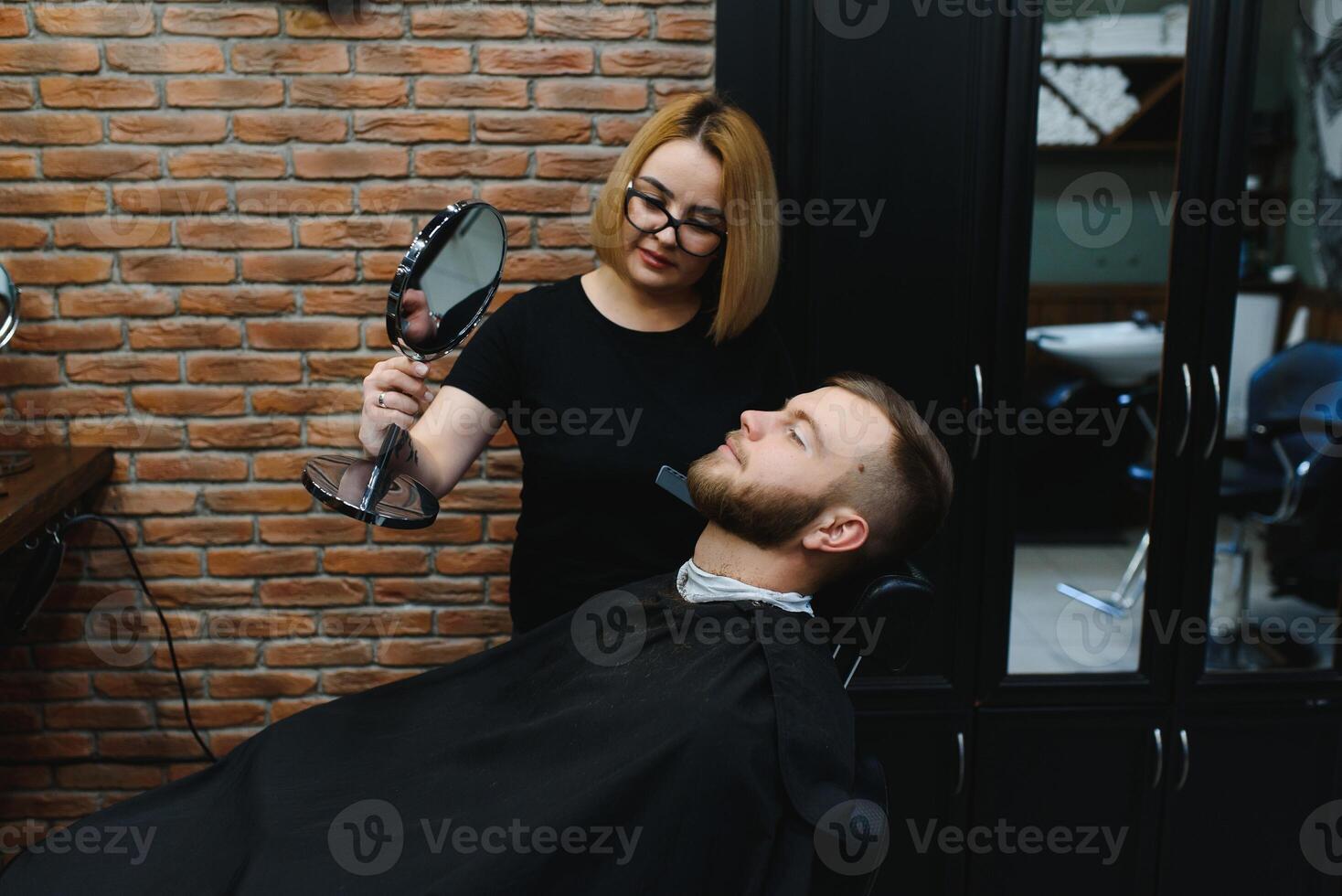 Barbershop or hairdresser concept. Woman hairdresser cuts beard with scissors. Man with long beard, mustache and stylish hair. Guy with modern hairstyle visiting hairdresser photo