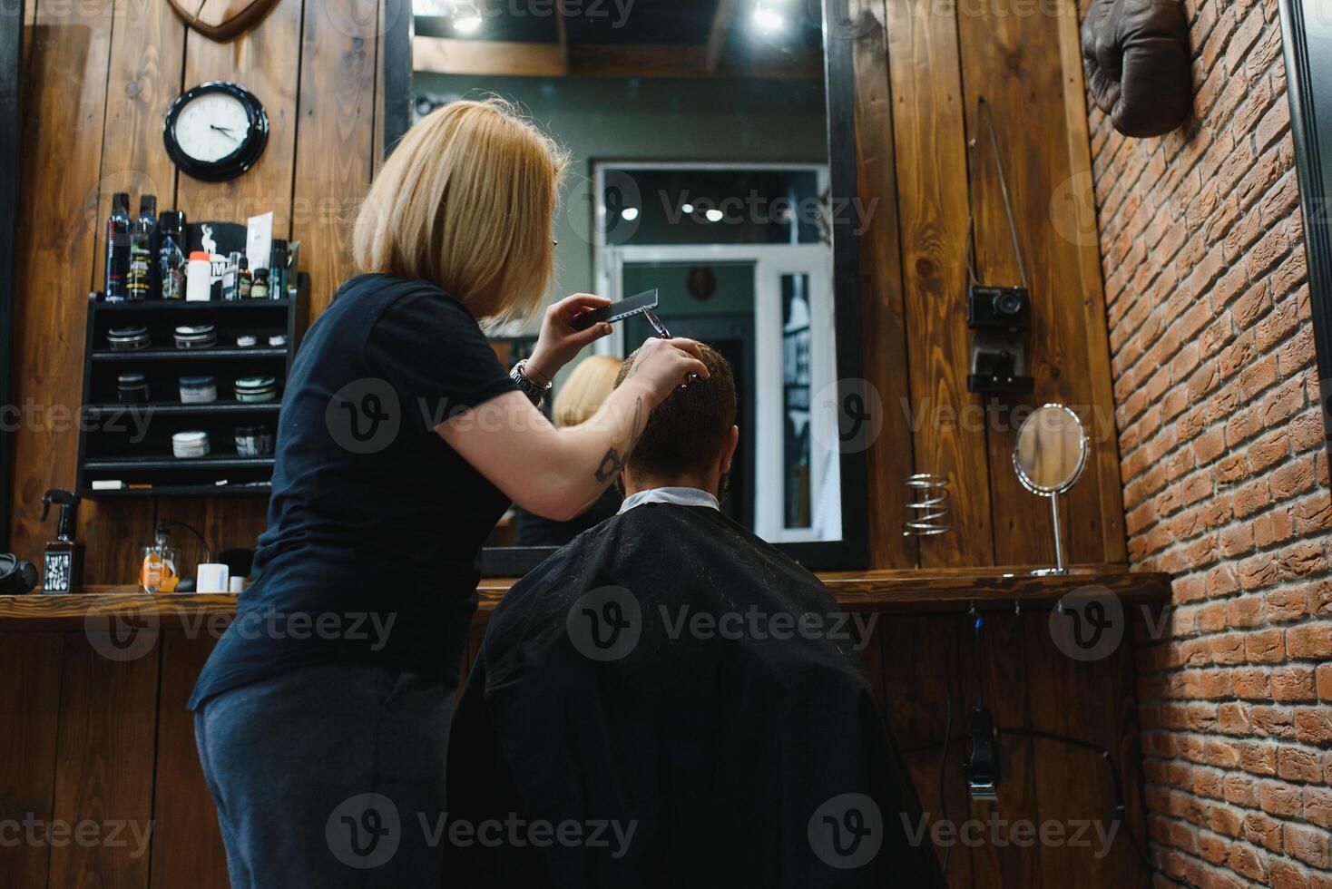 Stylish man sitting barber shop Hairstylist Hairdresser Woman cutting his hair Portrait handsome happy young bearded caucasian guy getting trendy haircut Attractive barber girl working serving client photo