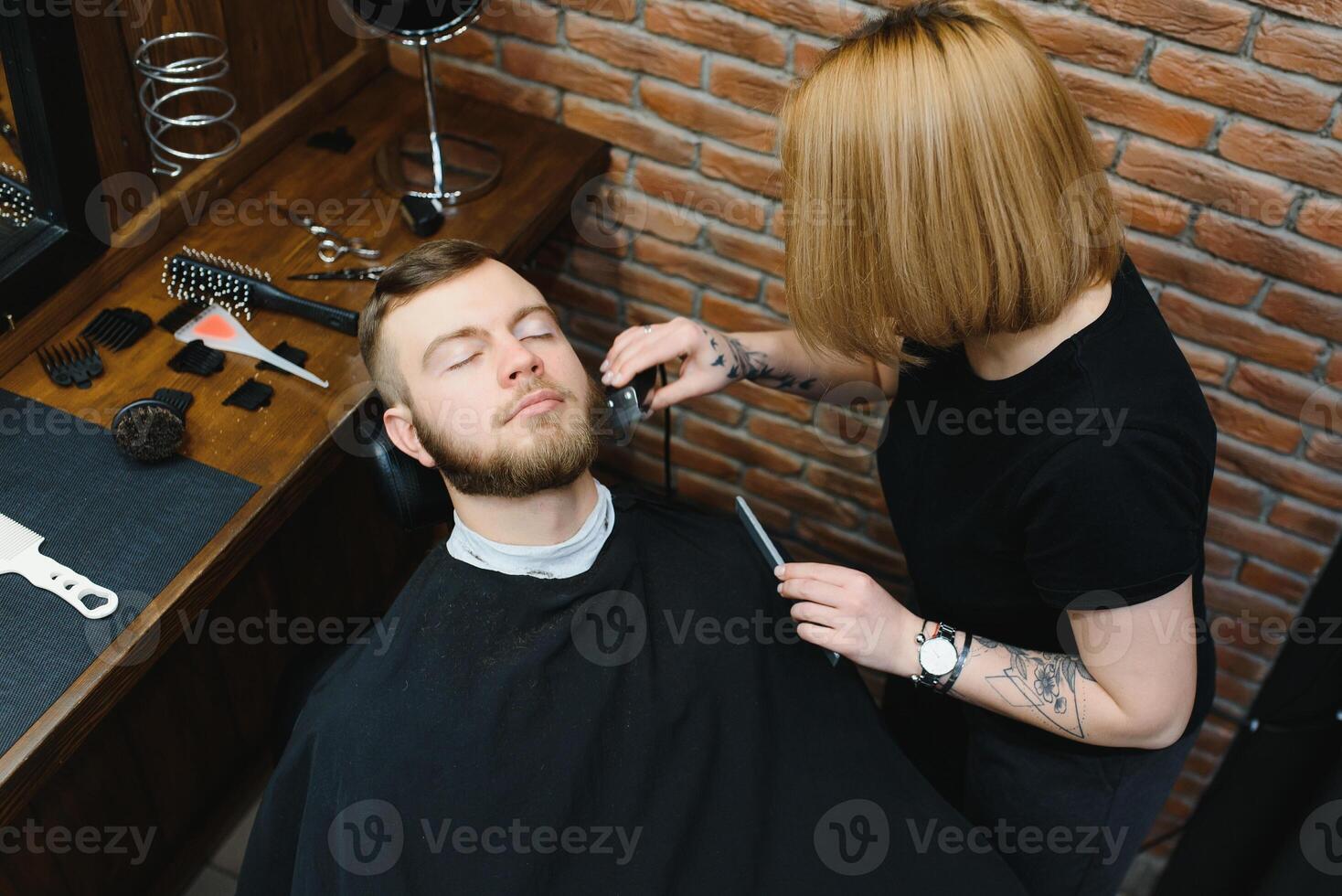 Client during beard shaving in barber shop photo