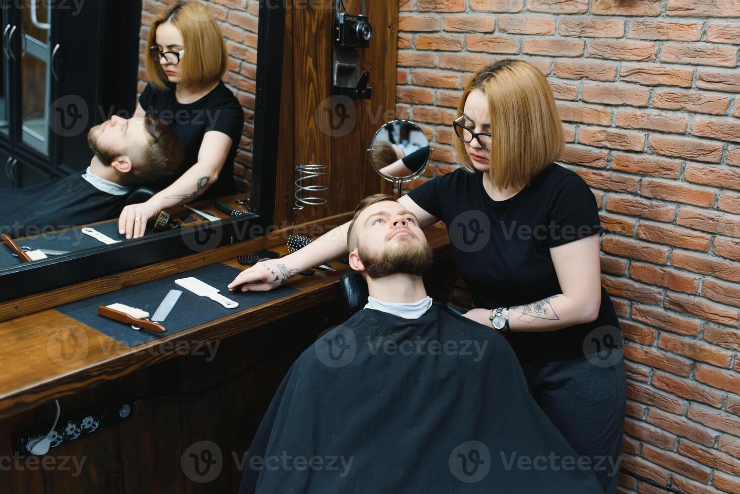 Client during beard shaving in barber shop photo