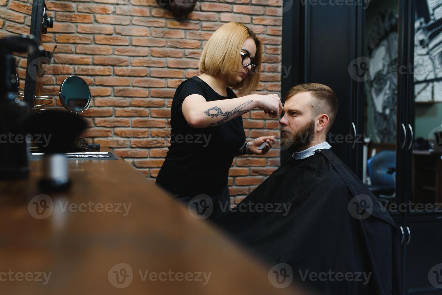 Stylish man sitting barber shop Hairstylist Hairdresser Woman cutting his hair Portrait handsome happy young bearded caucasian guy getting trendy haircut Attractive barber girl working serving client photo