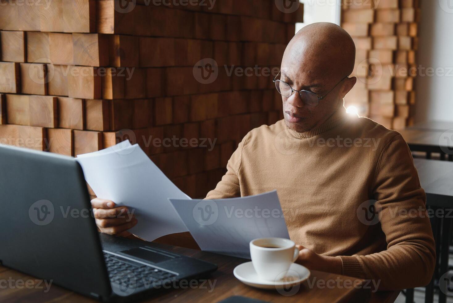 Portrait of smiling African American man in glasses sit at desk in office working on laptop, happy biracial male worker look at camera posing, busy using modern computer gadget at workplace. photo