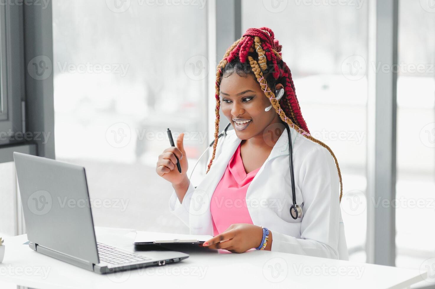 medicine, online service and healthcare concept - happy smiling african american female doctor or nurse with headset and laptop having conference or call at hospital. photo