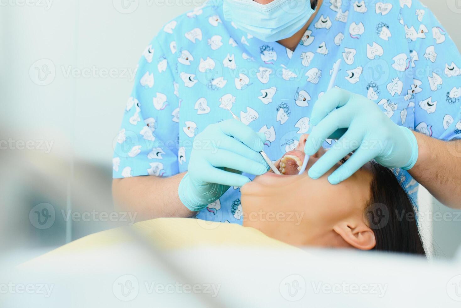 Midsection of male dentist adjusting apron on female patient before treatment in clinic photo