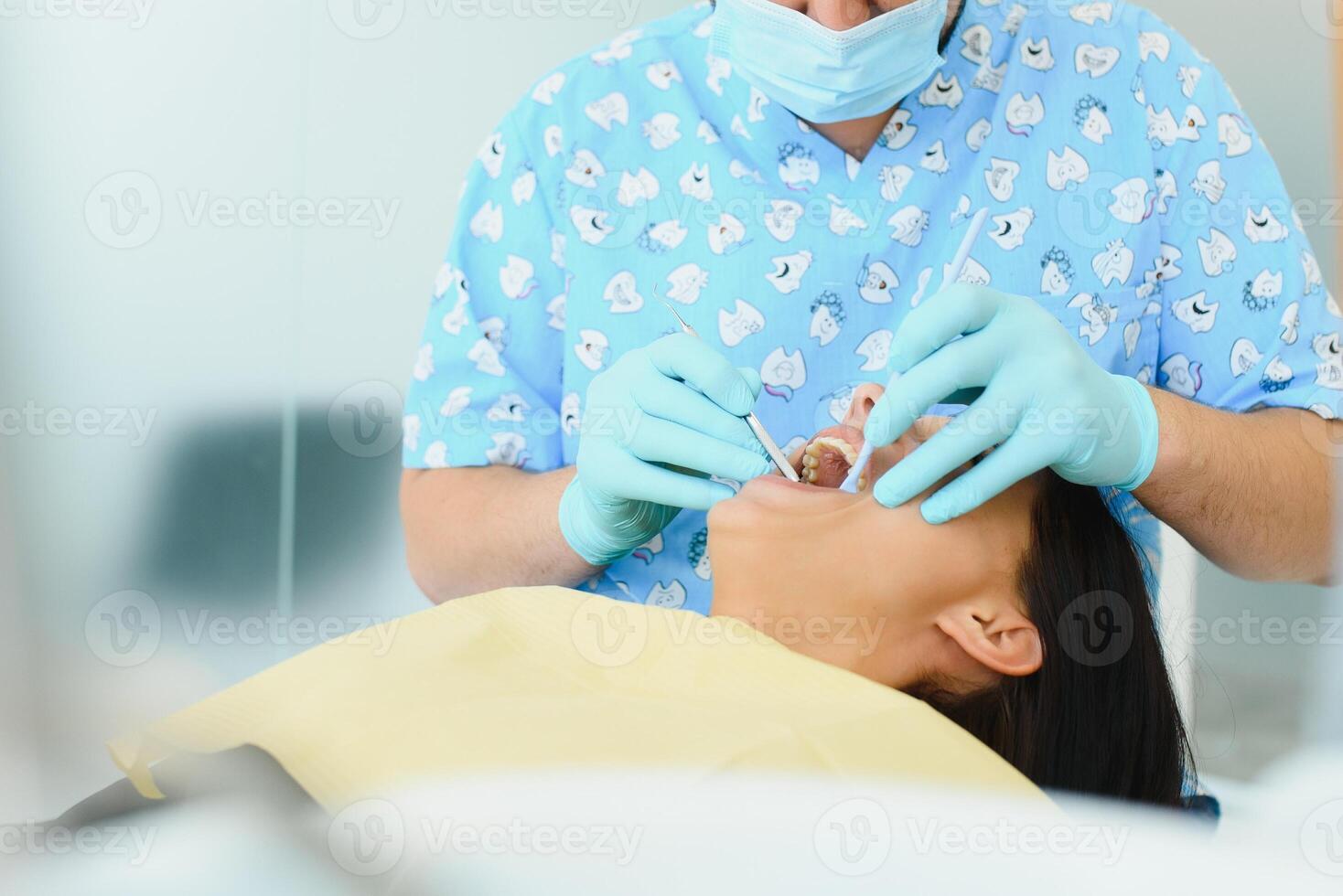 Midsection of male dentist adjusting apron on female patient before treatment in clinic photo