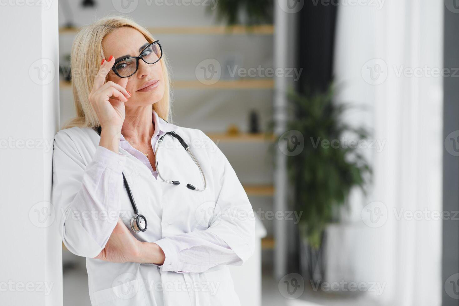 Female doctor wearing lab coat and stethoscope and holding clipboard in her hands while standing at hospital. photo