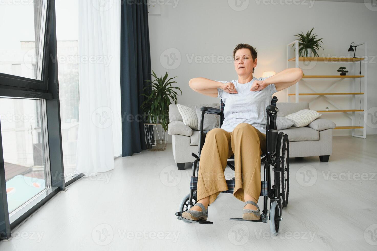 Woman in wheelchair working out in living room photo