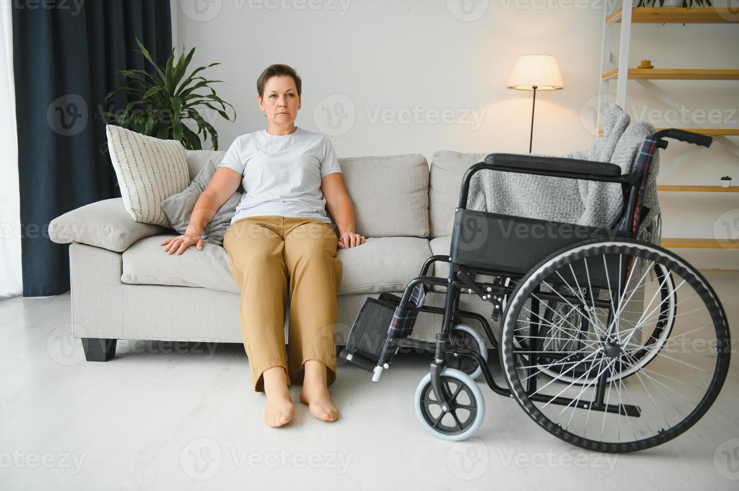 Brunette woman on couch near wheelchair photo