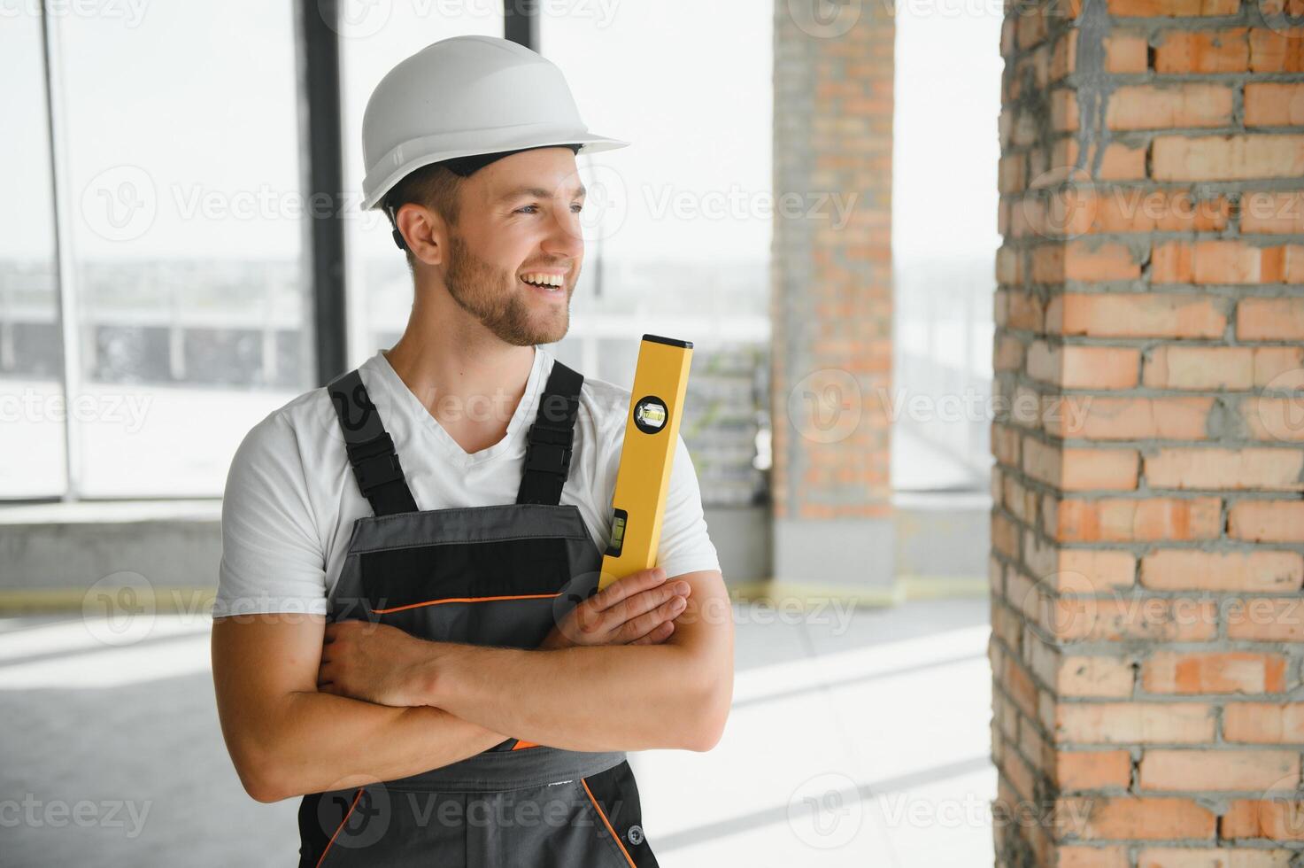Portrait of handsome male builder in overalls and hard hat photo
