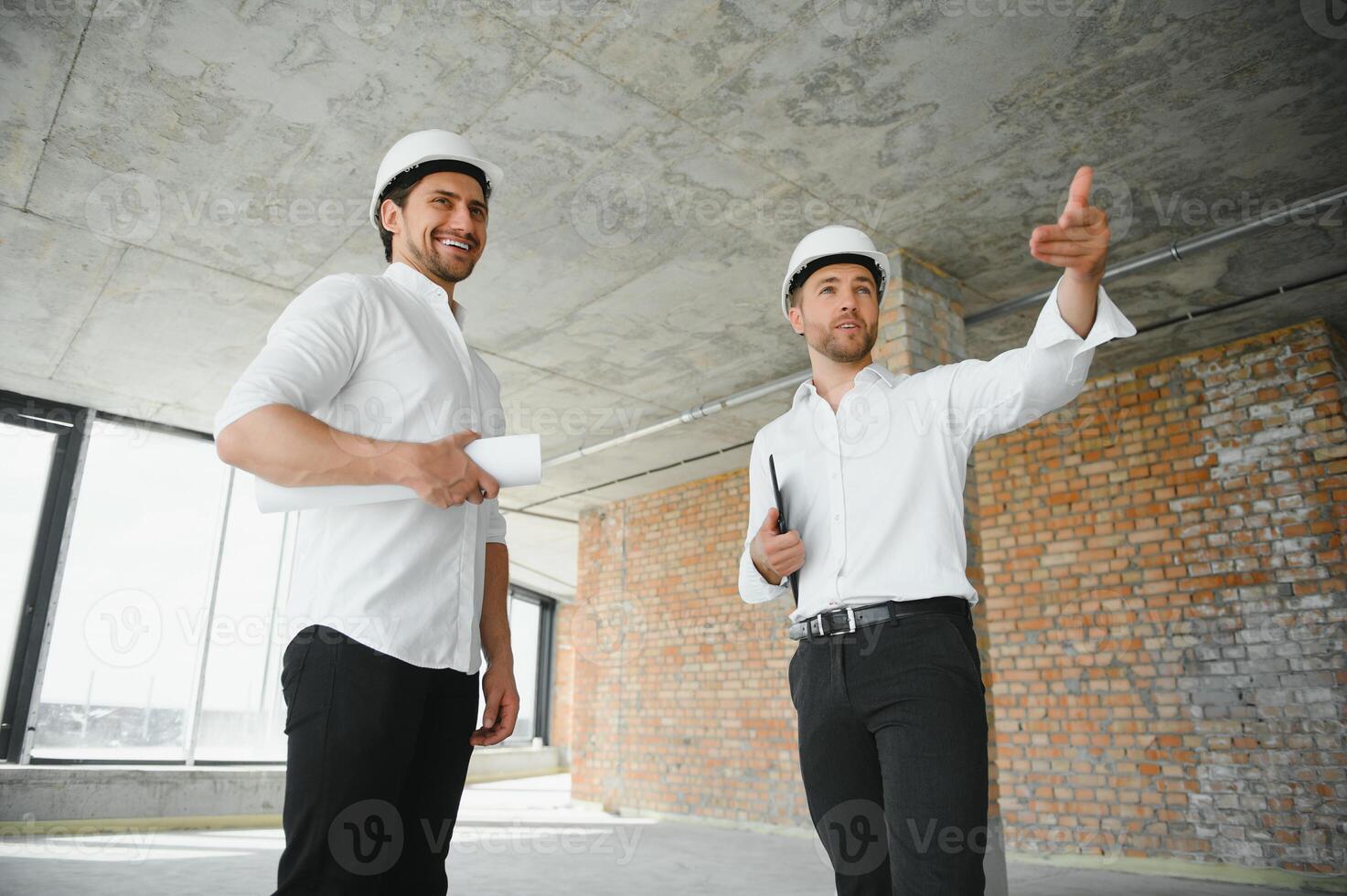 Two civil engineers or architects man inspecting construction of house. photo