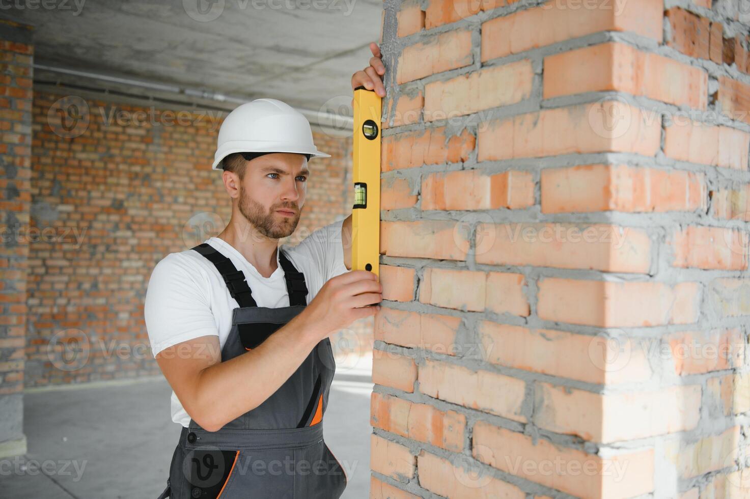 Portrait of handsome male builder in overalls and hard hat photo