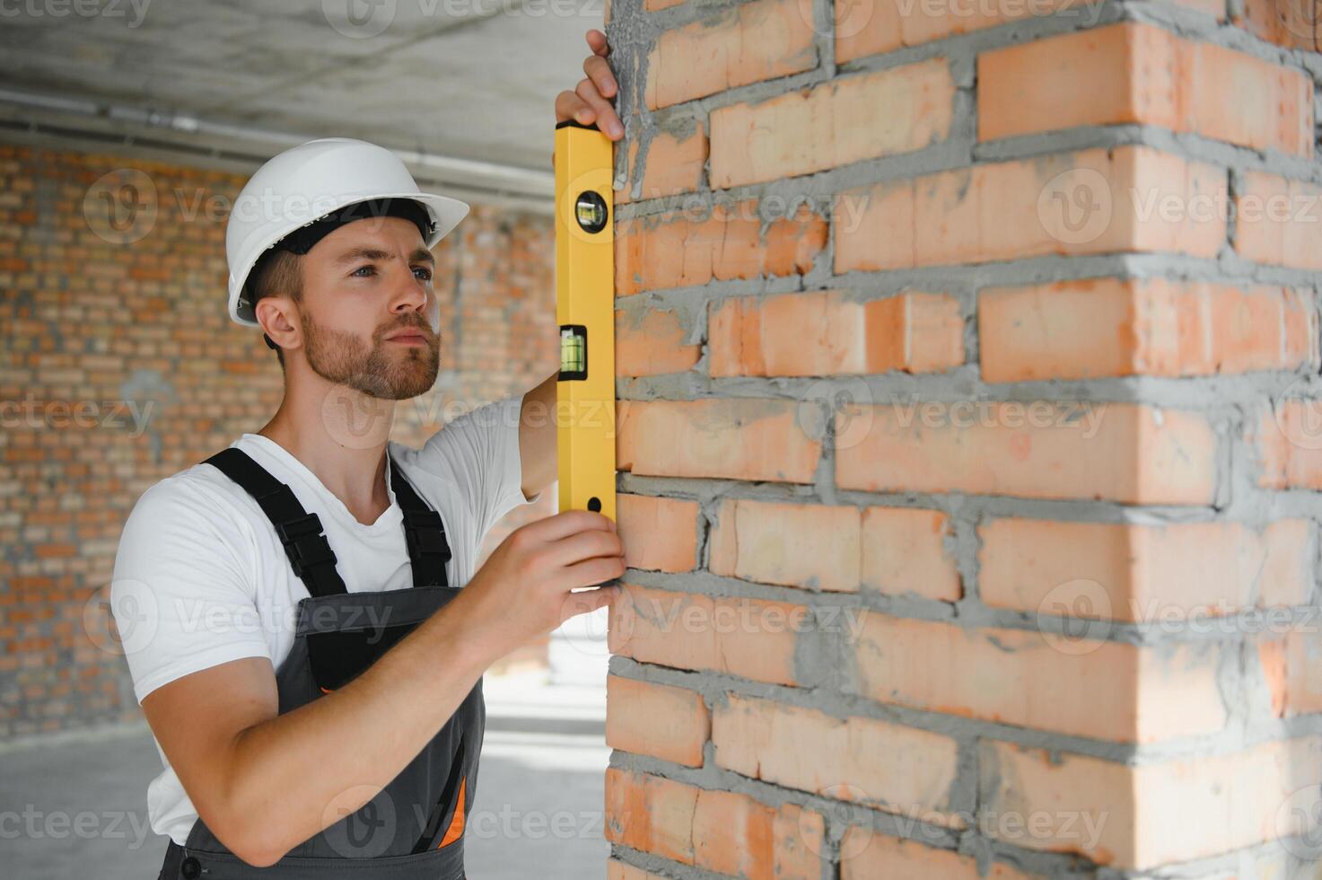Man builder working in construction site. Male repairer in overall and helmet. photo