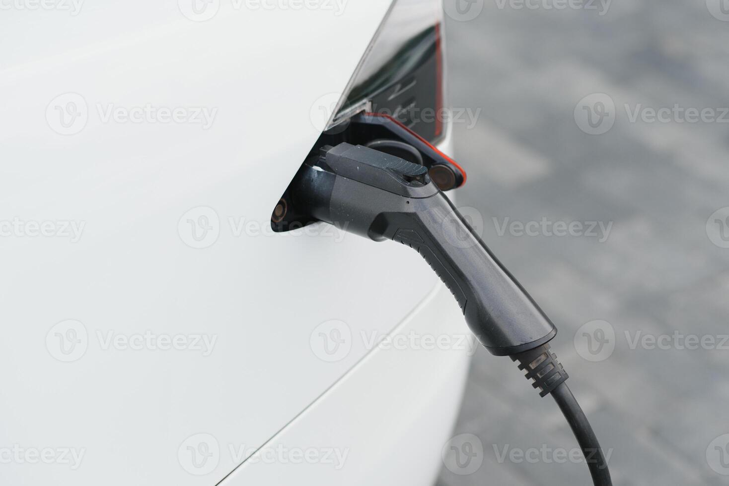 Close up of the Hybrid car electric charger station with power supply plugged into an electric car being charged. photo
