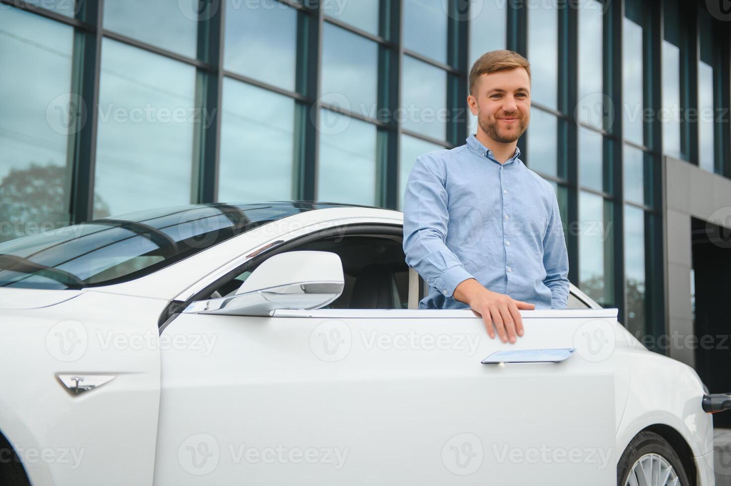 handsome young businessman standing near his car outdoors. photo