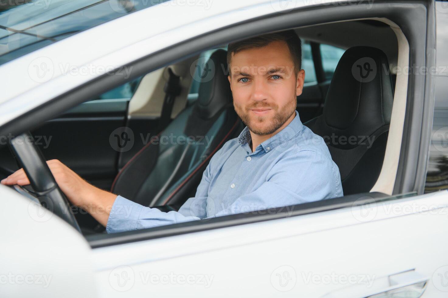 Businessman holding steering wheel while driving modern electric car on the street road. Confident man driving expensive car. Driver Turning Steering Wheel In Luxurious Auto On Trip photo