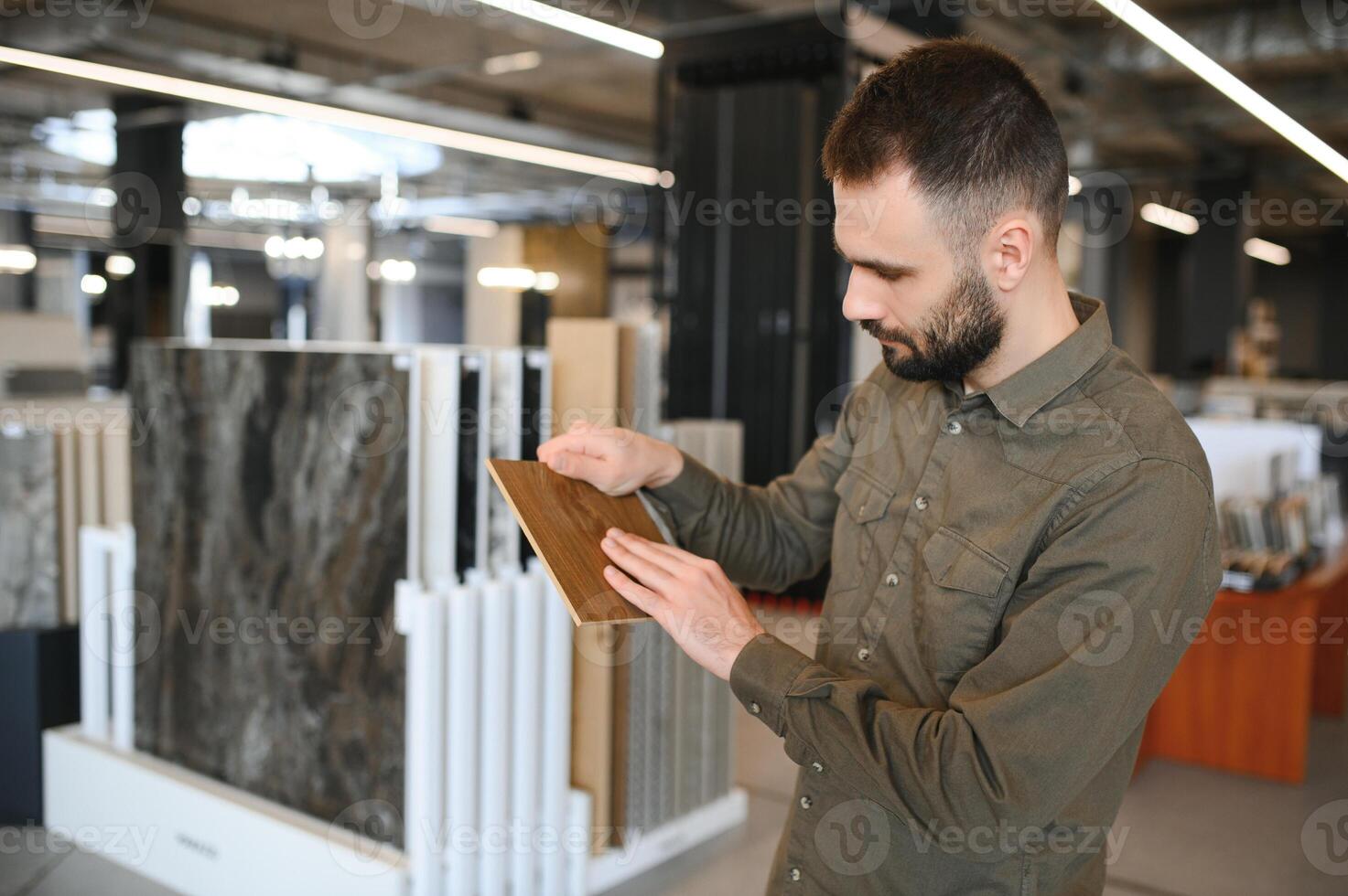 Man choosing tile among different samples in store photo