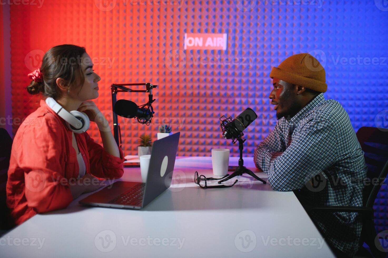 two radio hosts in headphones laughing while recording podcast in studio together photo