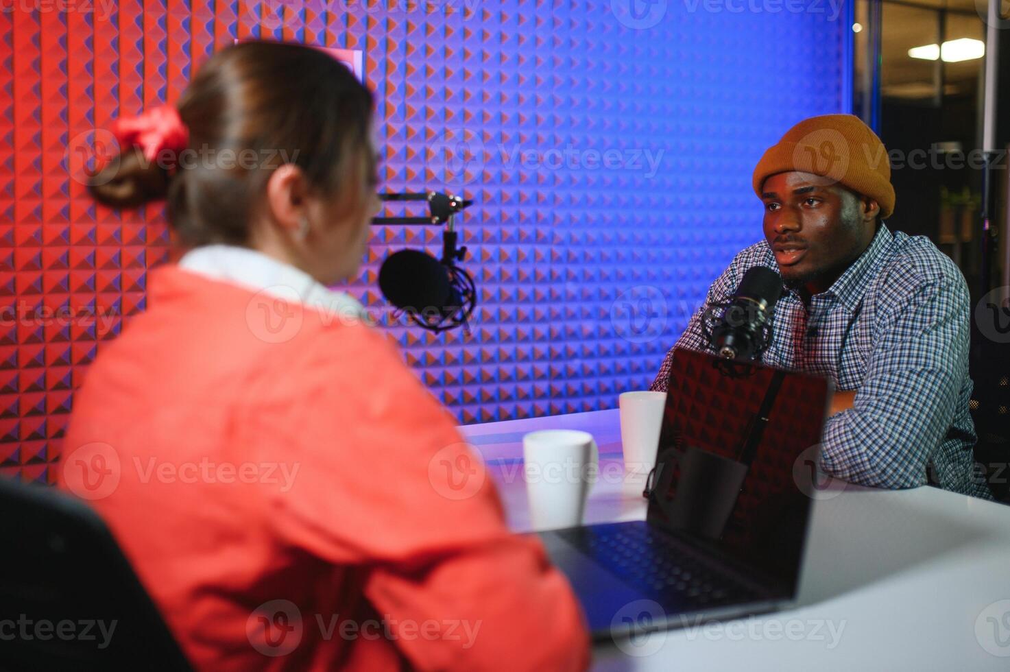 two radio hosts in headphones laughing while recording podcast in studio together photo