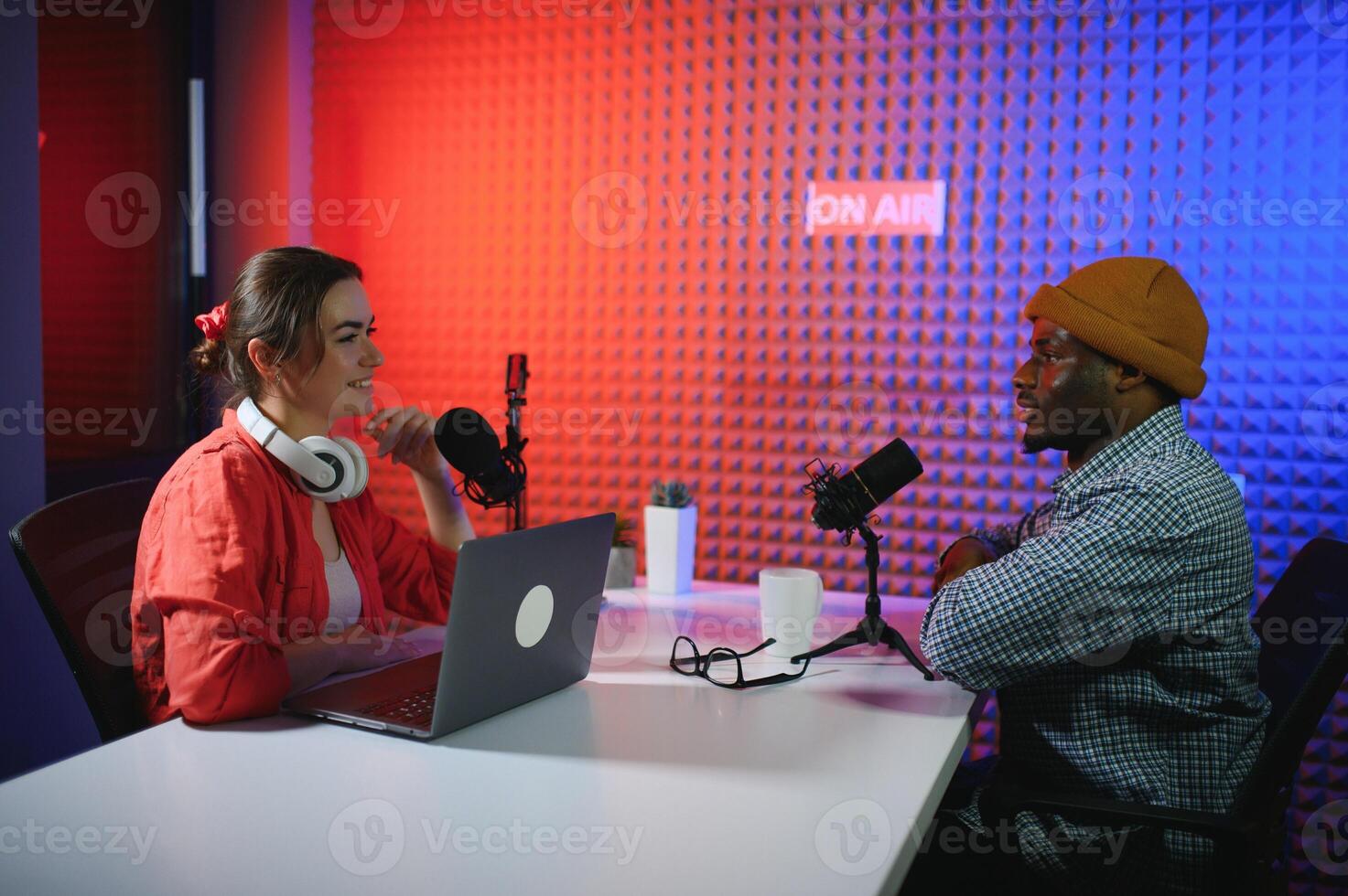 two radio hosts in headphones laughing while recording podcast in studio together photo