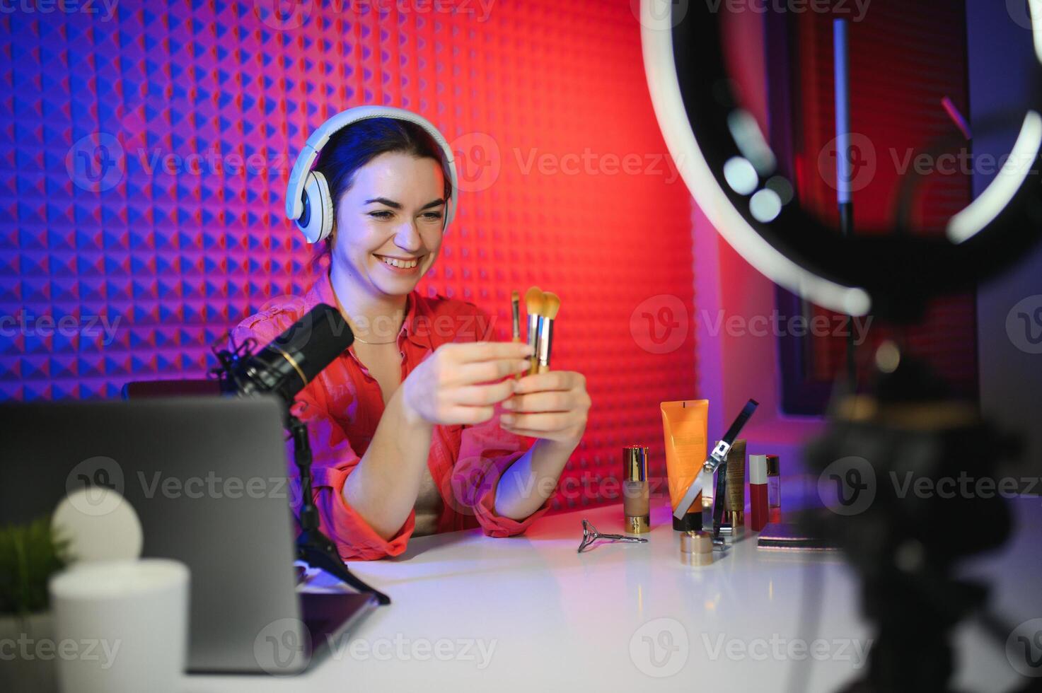 Beauty blogger woman filming daily make-up routine tutorial near camera on tripod photo