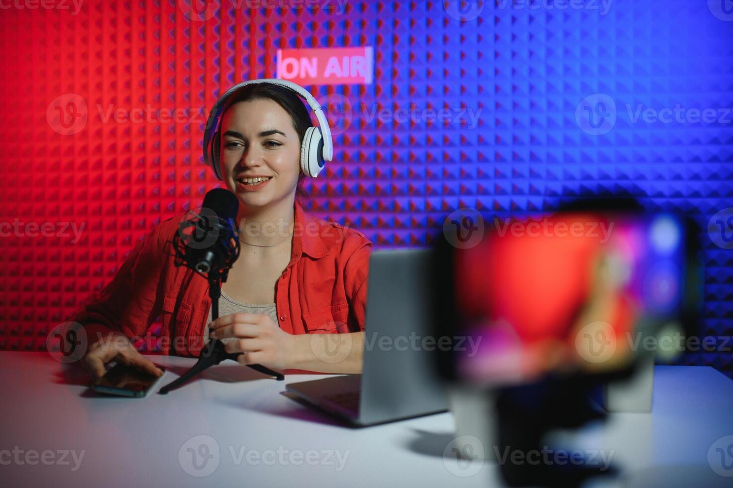 Young attractive woman blogger or vlogger looking at camera and talking on shooting with technology photo