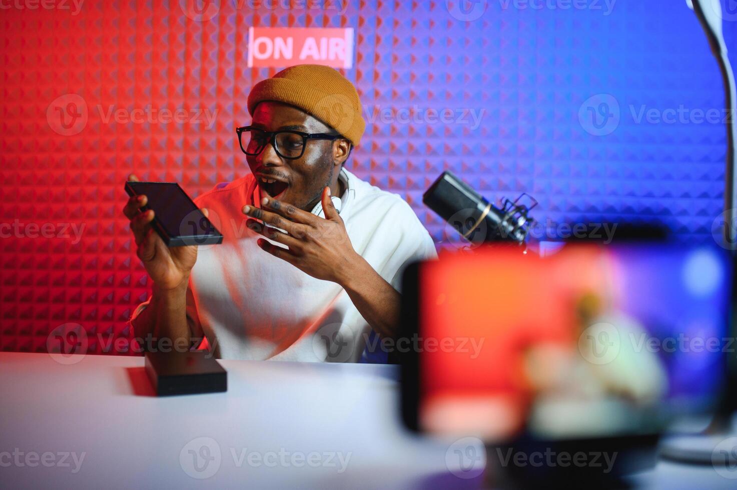 Young african american man recording or streaming podcast using microphone at his small broadcast studio. photo