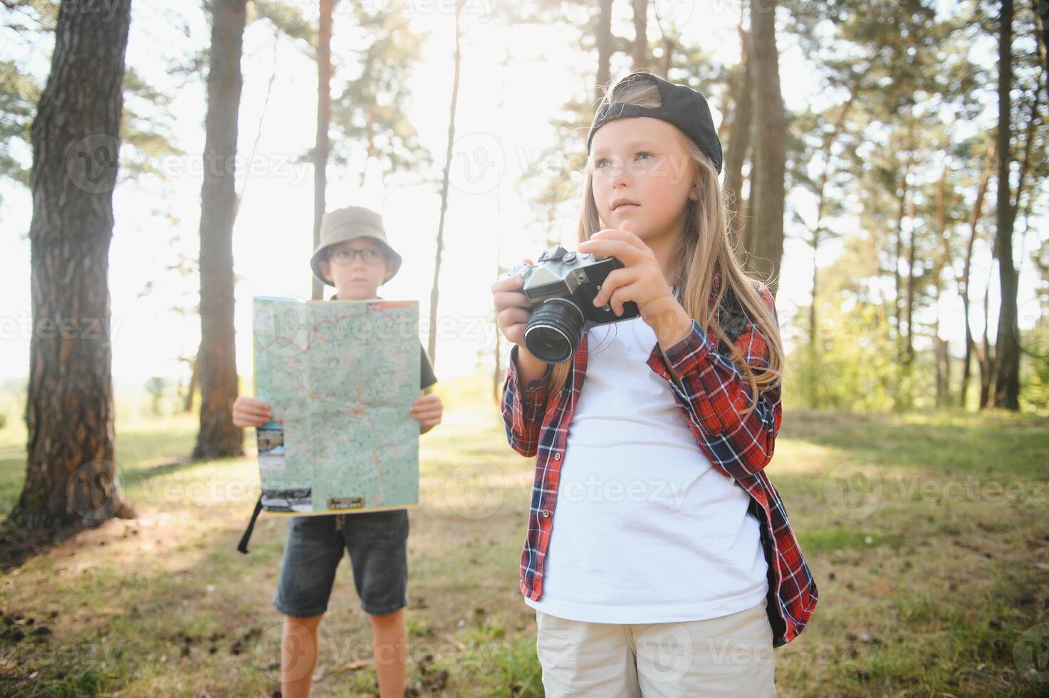 Happy excited school children with backpacks in casual clothes enjoying walk in forest on sunny autumn day, two active kids boy and girl running and playing together during camping trip in nature. photo