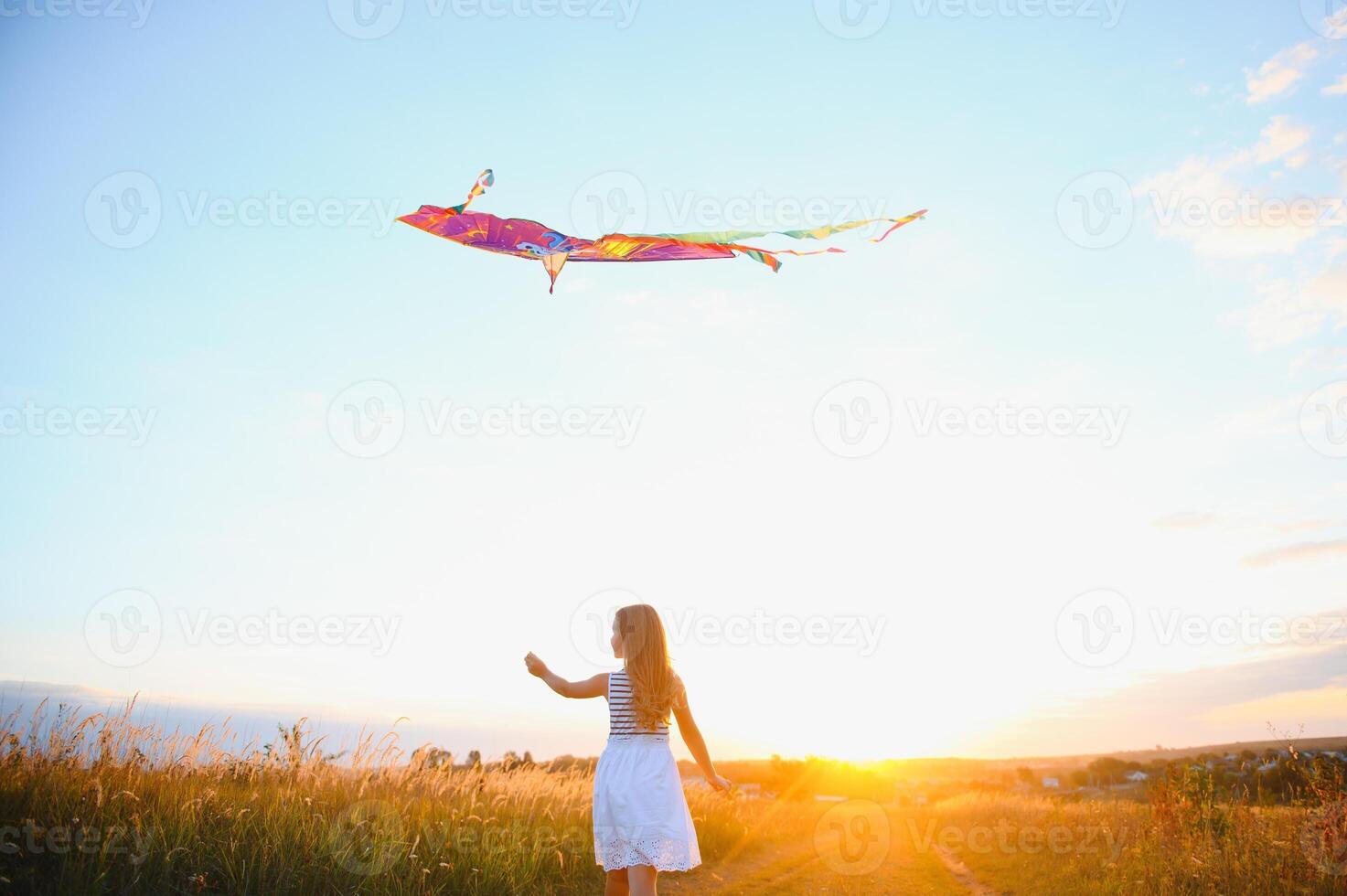 Little cute 7 years old girl running in the field with kite on summer day photo