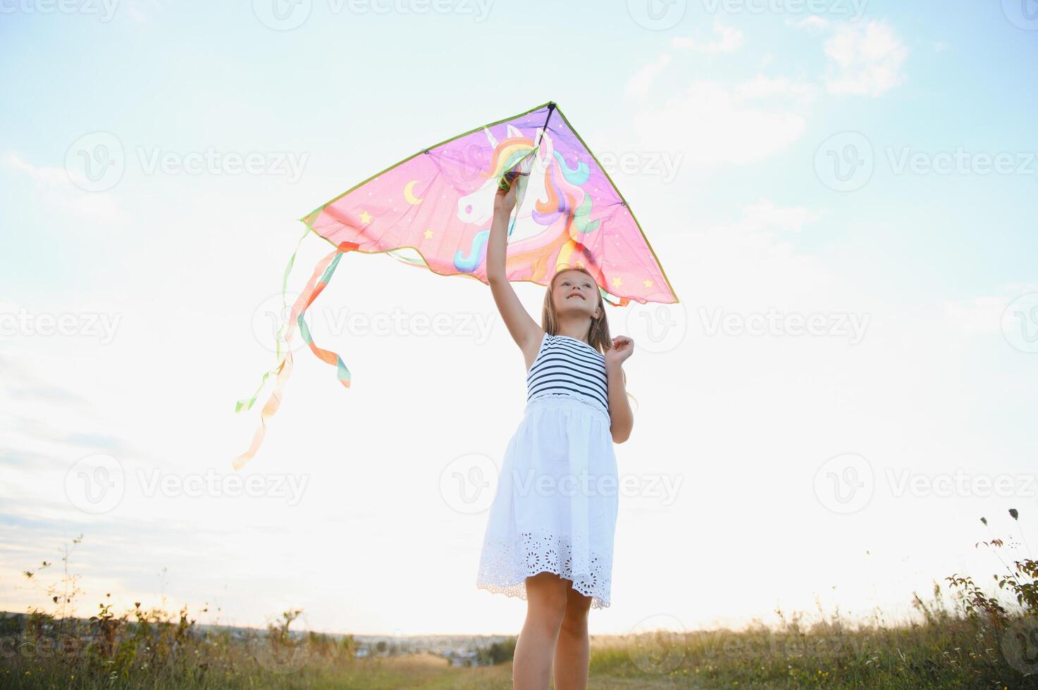 happy child girl with a kite running on meadow in summer in nature photo