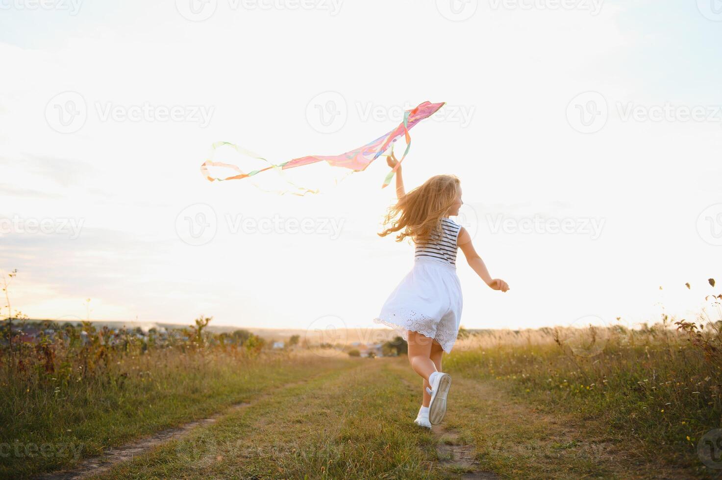 happy child girl with a kite running on meadow in summer in nature photo
