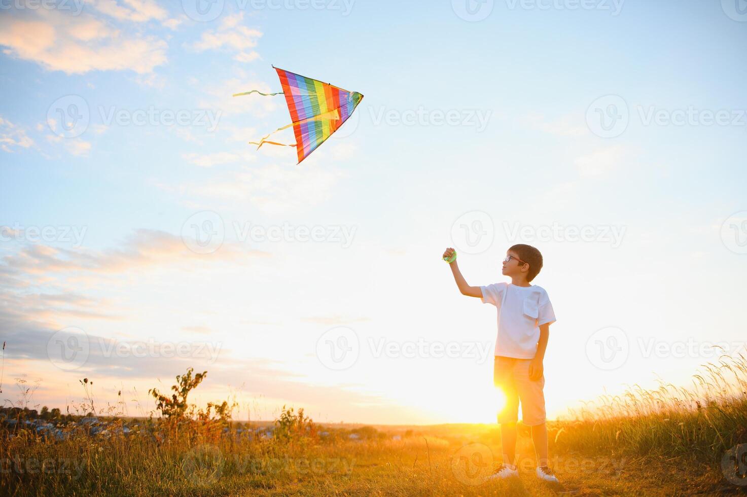 Boy is running with a kite during the day in the field photo