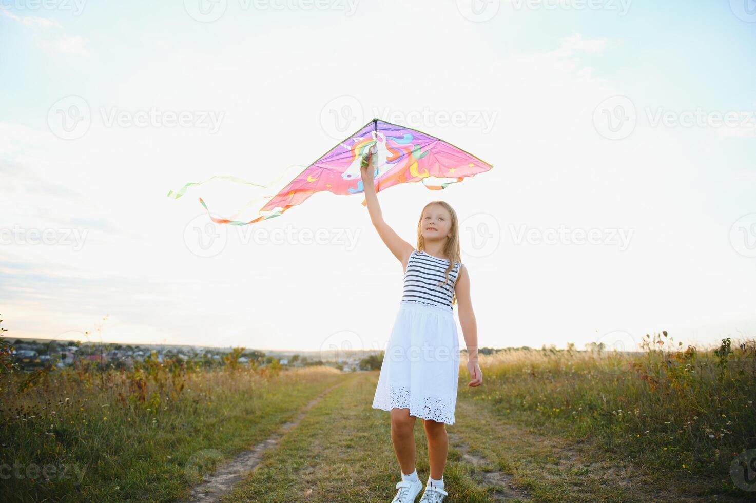 happy child girl with a kite running on meadow in summer in nature photo