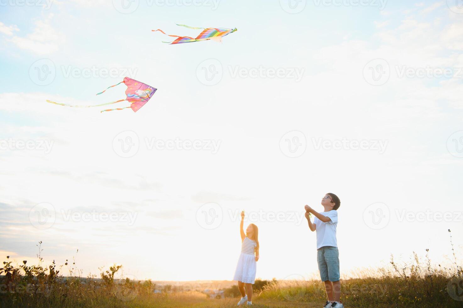 Children launch a kite in the field at sunset photo