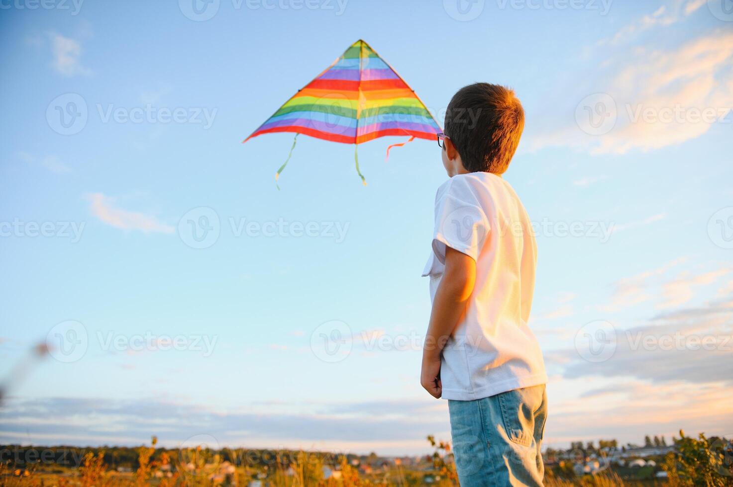 Little boy on summer vacation having fun and happy time flying kite on the field. photo