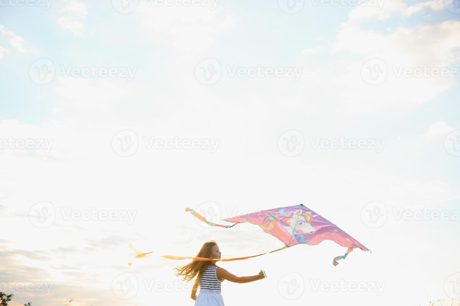 Little cute 7 years old girl running in the field with kite on summer day photo